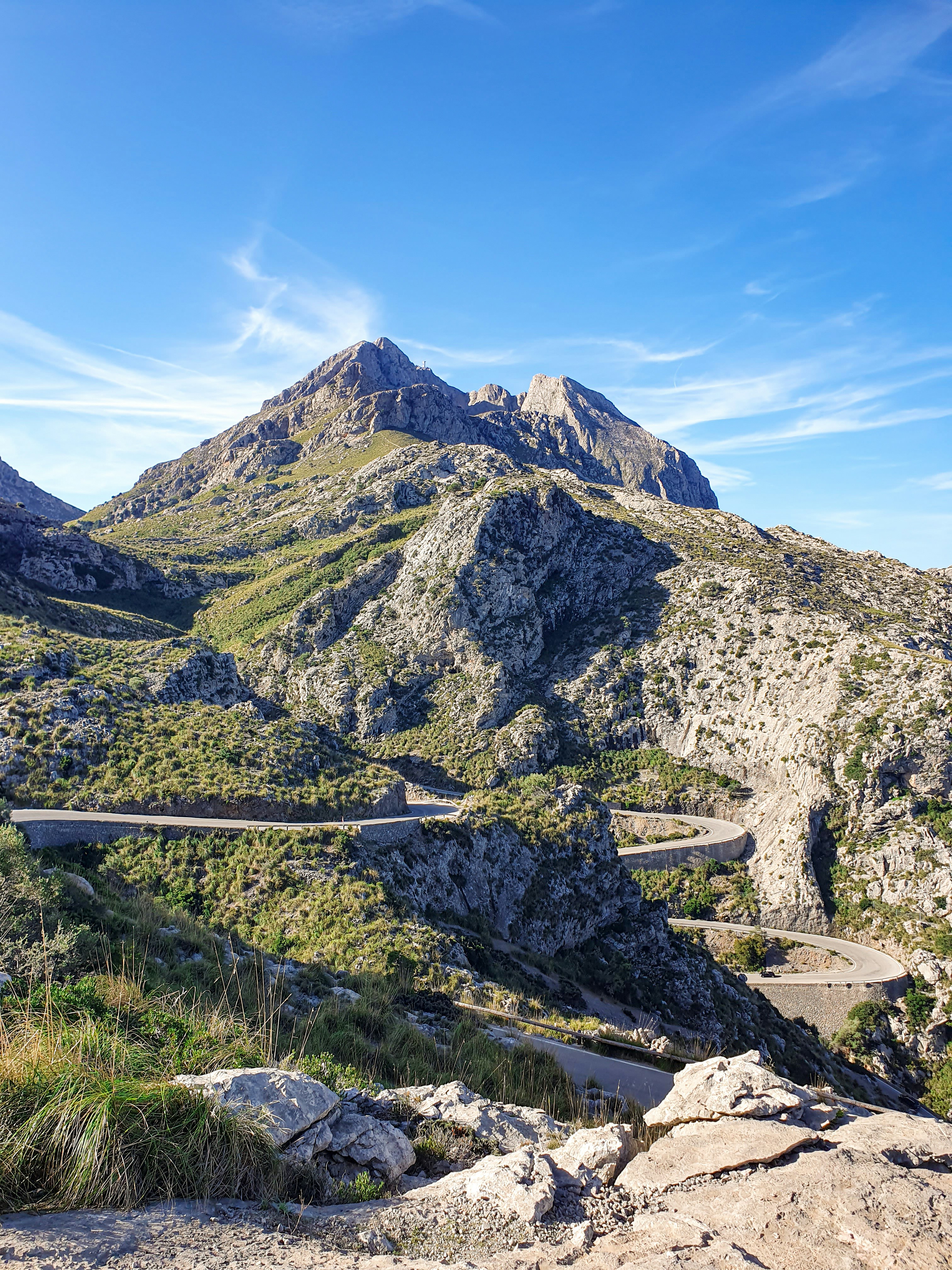 A narrow mountain road with steep switchbacks carved into the rock — the approach to Sa Calobra in Mallorca.